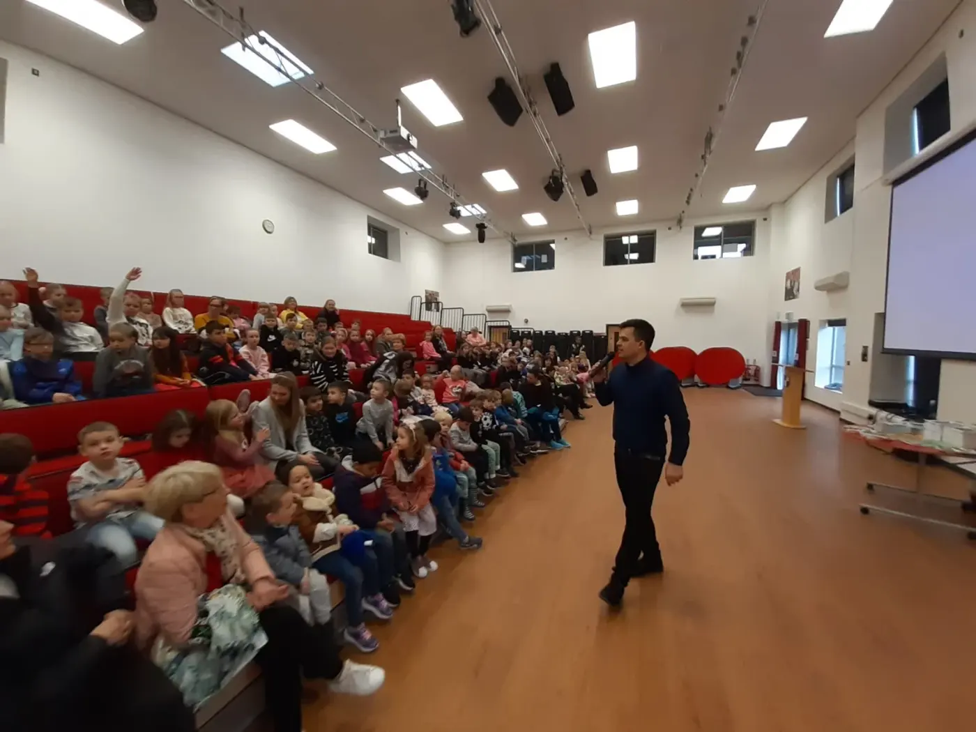 Wojciech Filaber speaking to a full auditorium of schoolchildren